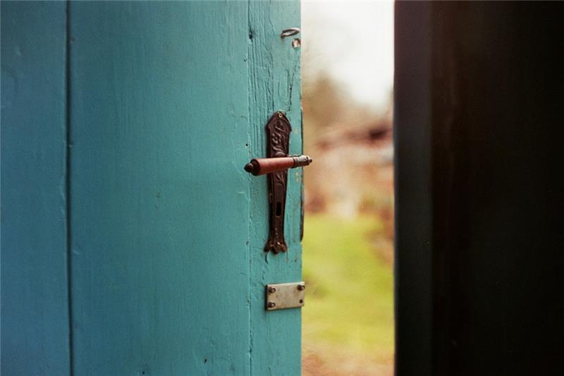 Slightly open door, green grass beyond