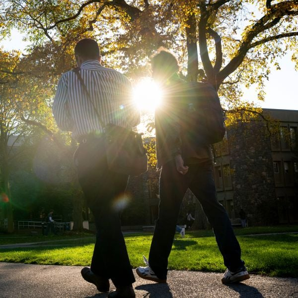 Two people walking with the sunset beyond us